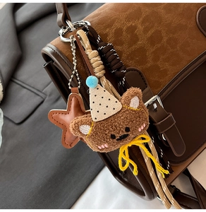 Detail of cute plush bear charm with yellow bow and leather star on a brown bag