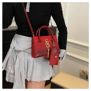 Detalle de bolso rojo con textura de cocodrilo, logo S dorado y mini monedero