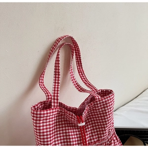 Detail view of red and white gingham canvas tote bag with drawstring texture and wide handles