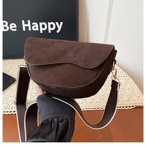 Detailed macro of dark brown suede saddle bag with fashion embossing and wide strap