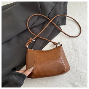 Detail shot of brown vintage leather shoulder bag with vertical stitching and knot strap