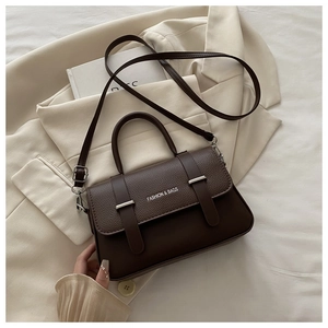 Detail of dark brown leather handbag featuring silver hardware and adjustable strap