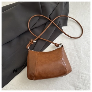 Close-up of brown vintage leather shoulder bag with vertical stitching and silver buckles