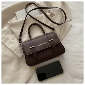 Close-up of litchi texture brown leather handbag with metal buckle and fashion logo