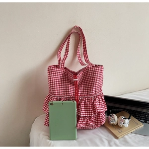 Detail of red gingham tote bag featuring ruffle edges and drawstring closure with tablet
