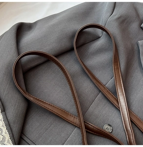 Detailed close-up of premium dark brown leather strap with precise stitching on gray suit