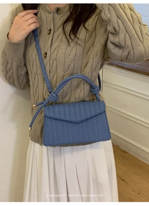 Blue woven texture handbag shown on model with a minimalist sophisticated retro vibe