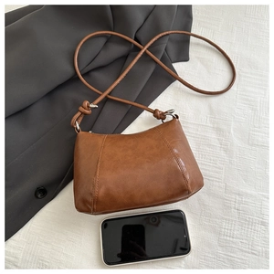 Macro view of brown matte leather crossbody bag with knot strap detail and stitching