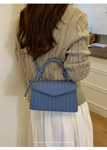 Blue woven crossbody bag worn by a model showcasing its chic minimalist retro aesthetic