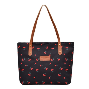 Black canvas tote bag with cherry print and brown leather handles on white background