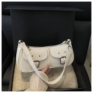 Close-up of beige vintage baguette bag with double pockets and dark metal buckles