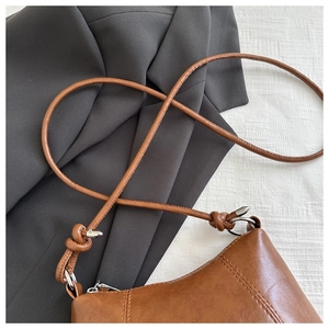 Detail of vintage brown leather bag with knotted strap and silver ring hardware