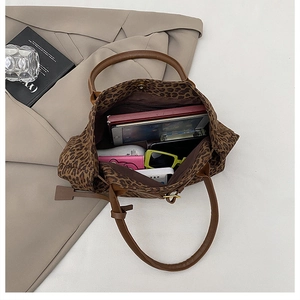 Macro shot of spacious leopard print tote interior with laptop and travel essentials