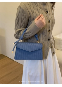 Blue woven minimalist handbag featuring a unique knotted handle with gold hardware