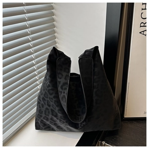 Detail of black leopard print tote bag with satin texture against white window shutters