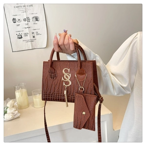 Bolso marrón con textura de cocodrilo, logotipo SS dorado y charm de monedero a juego