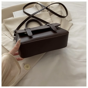 Detail of dark coffee leather flap bag with silver buckles and elegant top handle