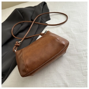 Detailed top view of a brown minimalist crossbody bag on a white textured background