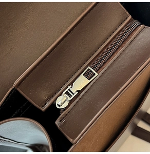 Detailed macro view of dark brown leather handbag with premium metal zipper and fine stitching