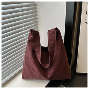 Detailed view of burgundy leopard print tote bag with glossy satin finish on a windowsill