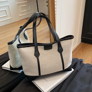 Elegant off-white canvas tote bag with black leather trim and handles for daily commute