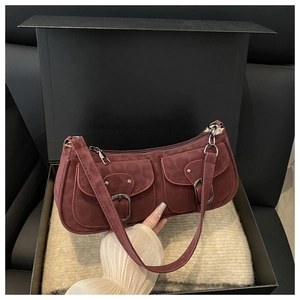 Detail of burgundy suede shoulder bag with dual buckle pockets in premium gift box