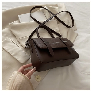 Detail of dark brown leather crossbody bag with silver buckles and elegant flap design