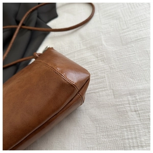 Detailed view of the brown leather bag bottom with high-quality stitching and round straps