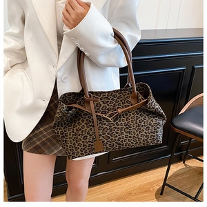 Leopard print tote bag with brown leather strap and decorative buckle on a model