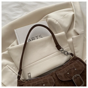 Detail der braunen Wildleder-Schultertasche mit Retro-Schnallen auf beigem Blazer