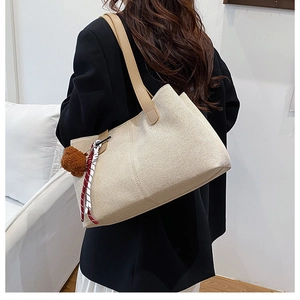 Vista posteriore di una modella con borsa tote in lino beige e cinturini in pelle a contrasto