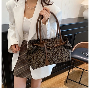 Detail view of large leopard print tote bag with brown leather handles and drawstring