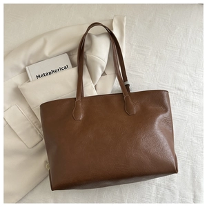 Detail view of large brown tote bag with premium matte texture on a white quilted background