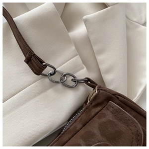 Nahaufnahme braune Wildleder-Baguette-Tasche mit schwarzer Metallkette und feiner Nahtarbeit