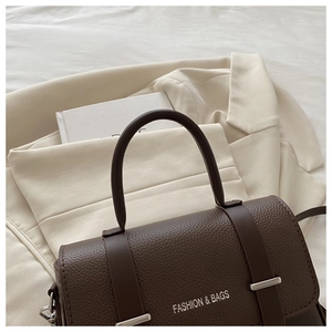 Detailed macro view of coffee brown lychee textured leather and silver fashion logo