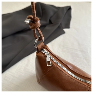 Detailed macro view of brown leather bag with fine stitching and silver zipper hardware