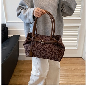Close-up of leopard print tote bag with brown leather handles and buckle detail