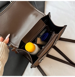 Detail view of the spacious inner compartments and zip pocket in this coffee brown bag