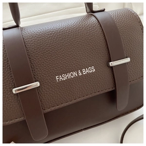 Detail shot of deep brown shoulder bag showing pebbled leather texture and silver buckle