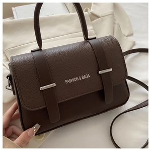 Detail of deep brown crossbody bag with silver buckle and fashion logo lettering