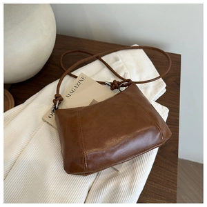 Detail shot of brown leather crossbody bag with silver hardware and unique knot design