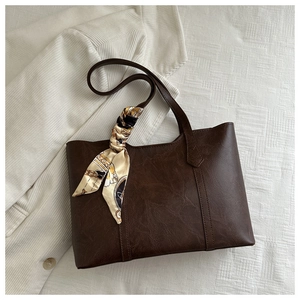 Detail der dunkelbraunen Vintage-Einkaufstasche mit elegantem bedrucktem Seidenschal