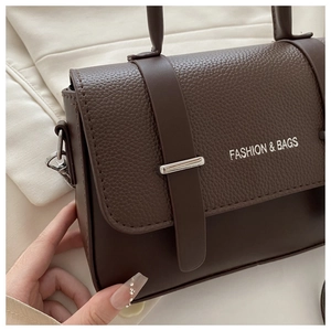 Detail of dark brown leather handbag featuring textured stitching and silver metal buckle