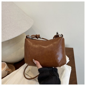 Detailed shot of brown faux leather hobo bag with vintage texture and knotted rope strap
