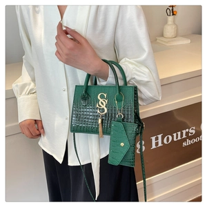 Bolso tote verde oscuro con textura de cocodrilo, logo SS dorado y borla de adorno