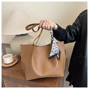Brown faux leather tote bag detail with decorative silk scarf on handle and soft texture