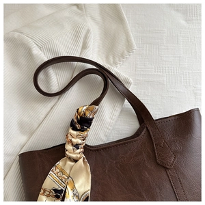 Close-up of deep coffee tote bag with lychee texture and silk scarf accessory