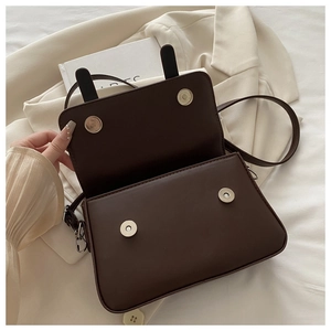 Detail view of small coffee leather crossbody bag with dual magnetic closures and ear accents