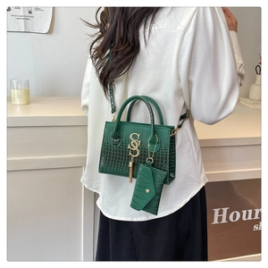 Detalle de bolso verde oscuro de cocodrilo con logo SS dorado y borlas de metal