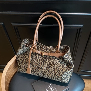 Fashionable leopard print tote bag with brown leather straps displayed on a chair